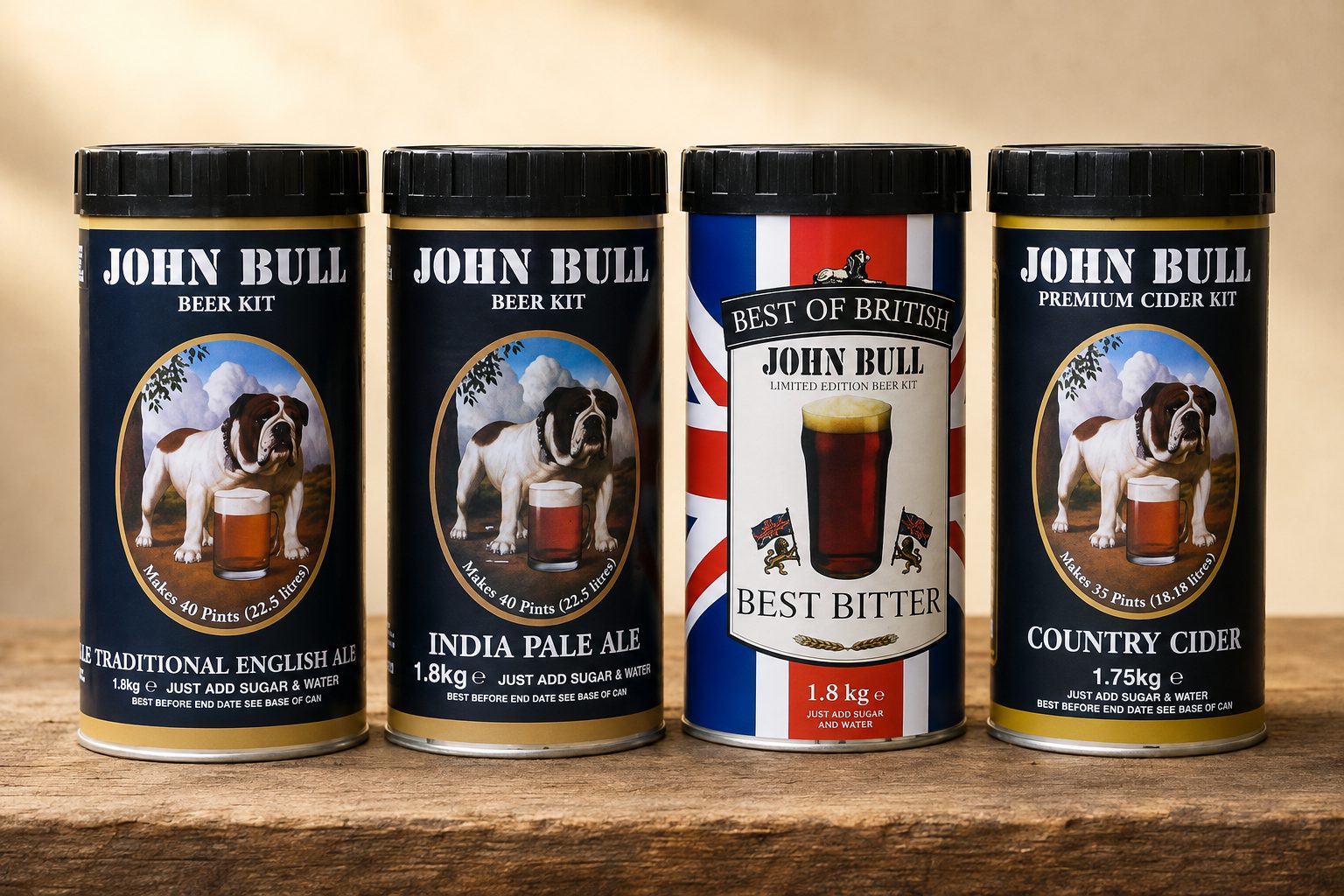 The four John Bull Standard Class kit cans standing in a row on a wooden bench: Traditional English Ale, India Pale Ale, Best Bitter in Union Jack livery, and Country Cider.